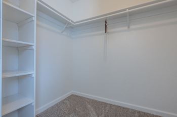 A walk in closet with white walls and shelves
